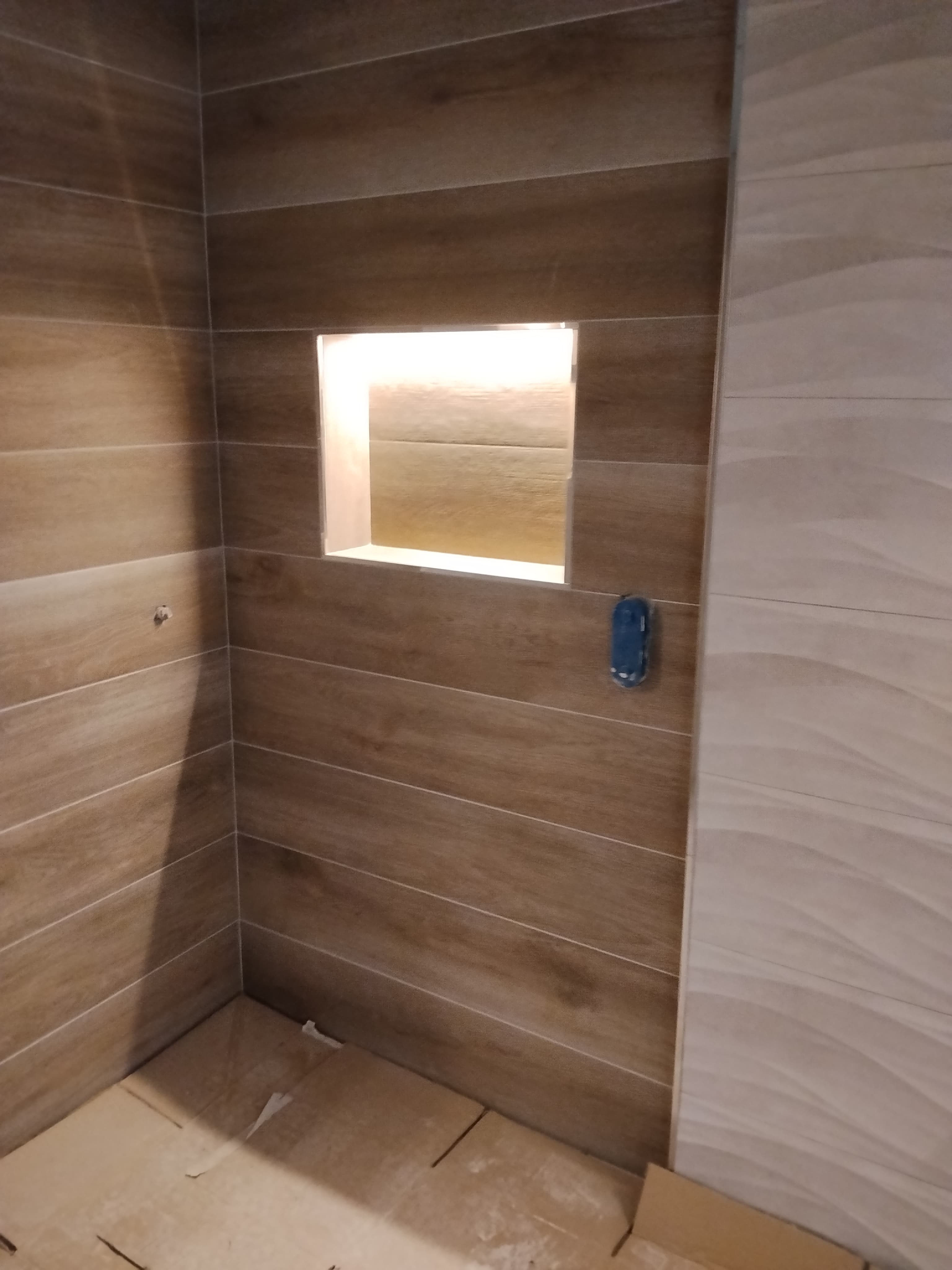 Pared de baño alicatada en tonos madera y blanco